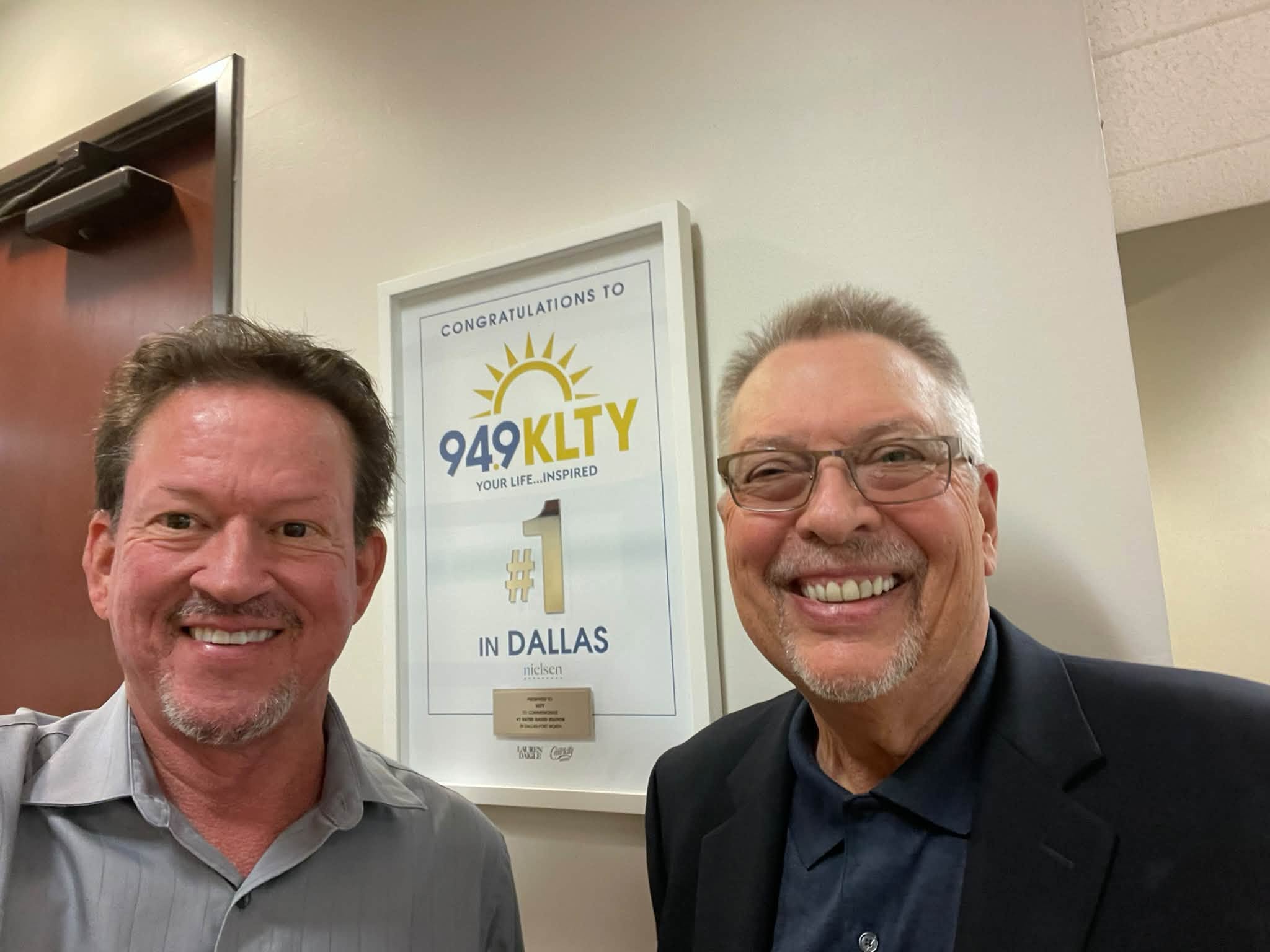 Frank Reed and a colleague beside a framed KLTY “#1 in Dallas” recognition